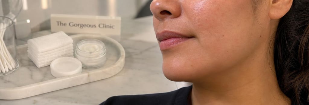 Photorealistic close-up of a Latina woman's lower face and jawline, skin-texture detail, soft clinical lighting, subtle aftercare cream jar and gauze on a marble tray, editorial medical aesthetic still life, no logos, natural skin tones.
