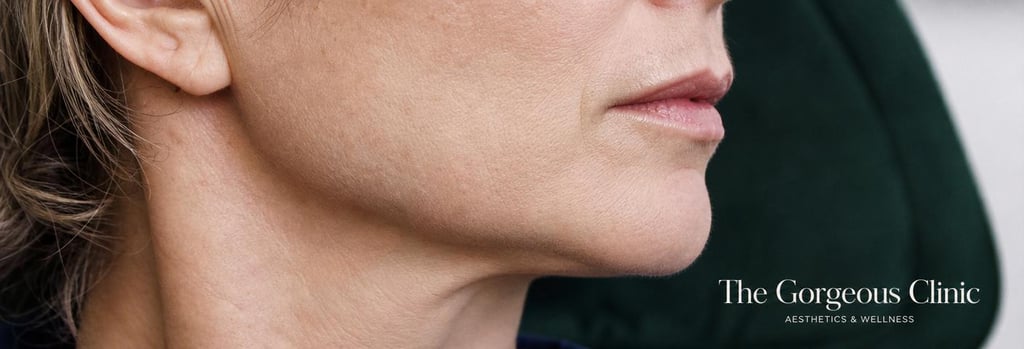 Photorealistic close-up of a mature jawline in soft clinical lighting, minimal retouching, realistic skin texture, subtle definition, forest green upholstery blurred in background, editorial feel