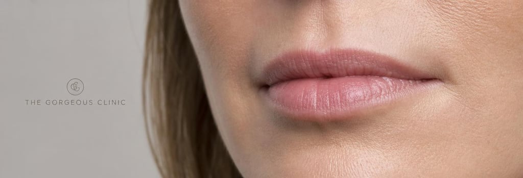 Photorealistic close-up of lips in soft clinical lighting, natural mature skin texture, slight asymmetry visible, shallow depth of field, negative space, premium clinical editorial feel, no exaggerated volume, calm tones, tangible skin pores.