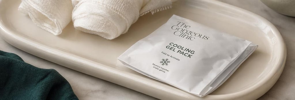 Photorealistic close-up of a small folded cooling gel pack resting on a cream ceramic tray, gauze nearby, forest green cloth hint, soft light, editorial aftercare still life connected to injectable treatments.